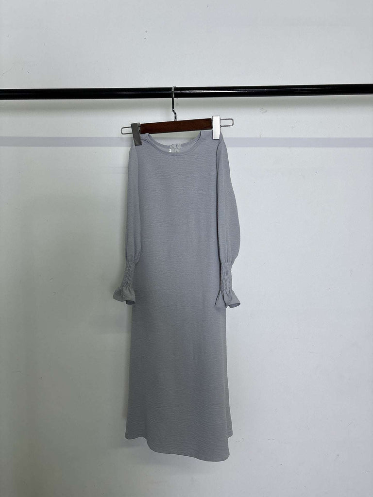 Long sleeve round neck wavy ruffled solid color polyester dress hanging on wooden hanger