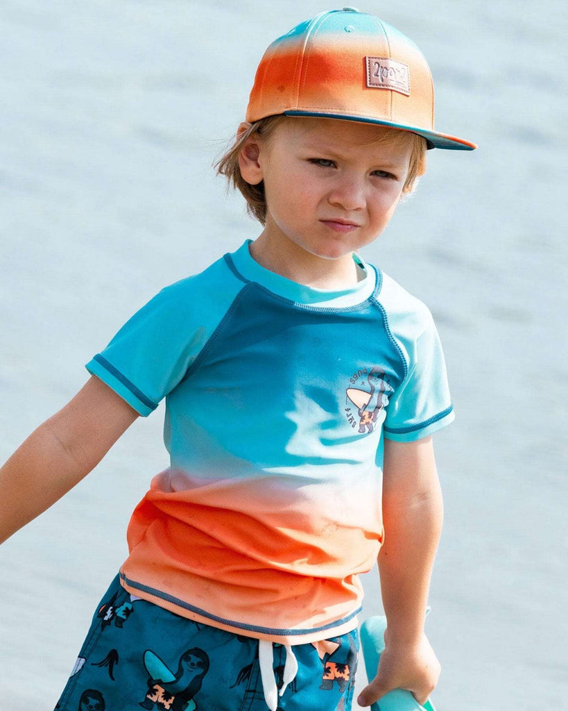 Garçon portant t-shirt et casquette colorés en bord de mer