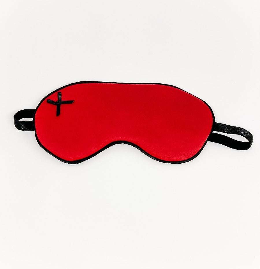 Red satin sleep mask with black trim and elastic straps for comfortable light blocking