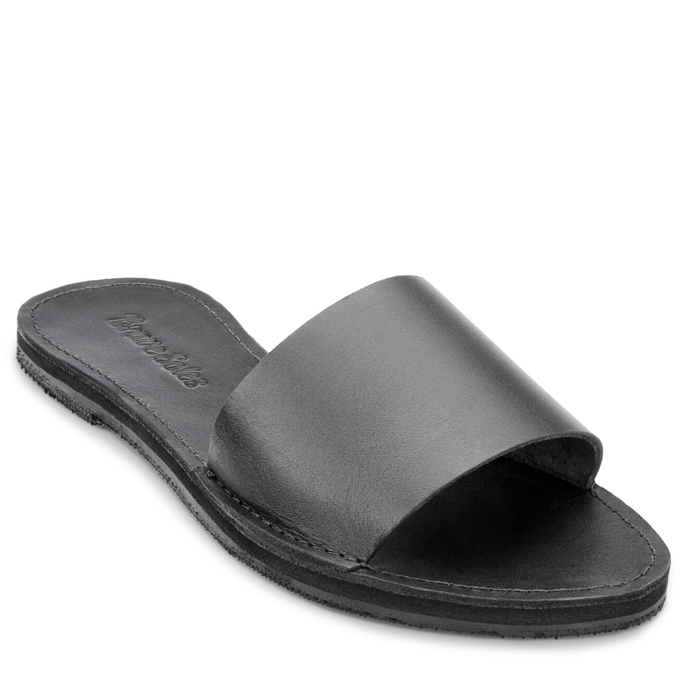 The Linda Leather Slide is a black handcrafted leather slide sandal with a cushy foam mid-sole and hand-cut sole from upcycled tires, designed for instant comfort and elegant style.