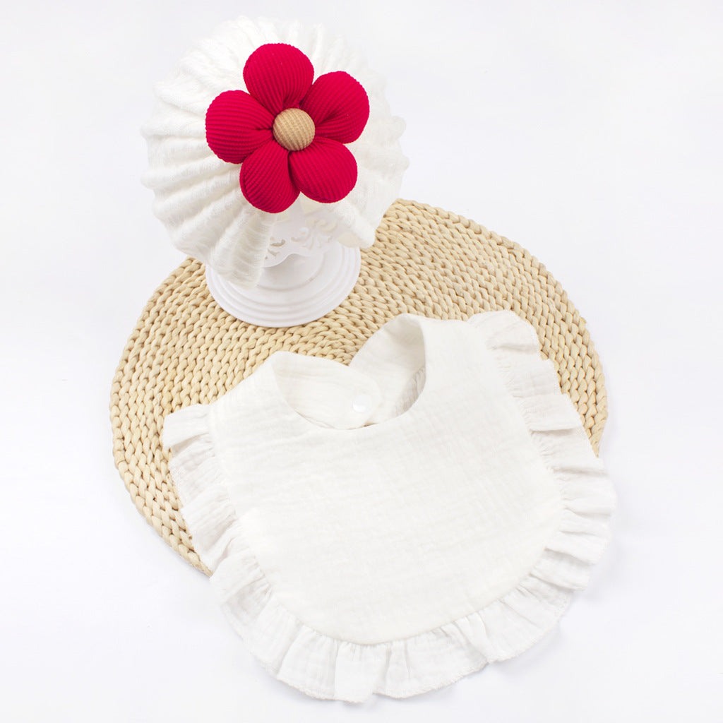 Organic cotton newborn baby hat and bib set with frilly trim, soft muslin fabric, and red flower decoration