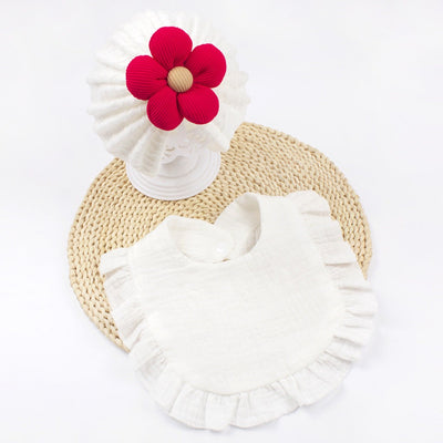 Organic cotton newborn baby hat and bib set with frilly trim, soft muslin fabric, and red flower decoration
