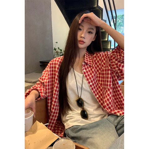 Woman wearing red plaid shirt cardigan with long sleeves and loose fit sitting indoors