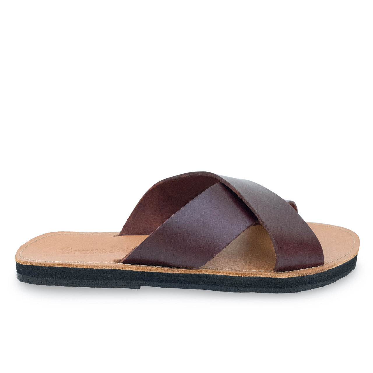 Side view of genuine leather slides with crisscross straps, cushioned footbed, and black upcycled tire sole.
