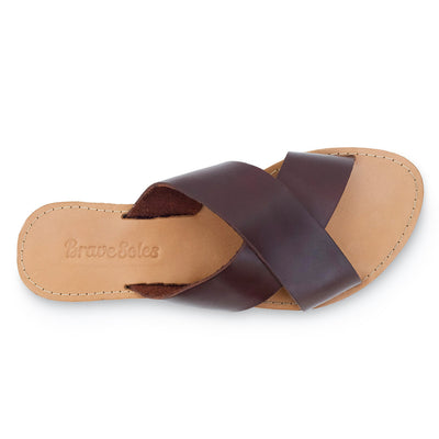 Genuine leather slides with crisscross straps, cushioned footbed, and durable upcycled tire sole for sustainable comfort.