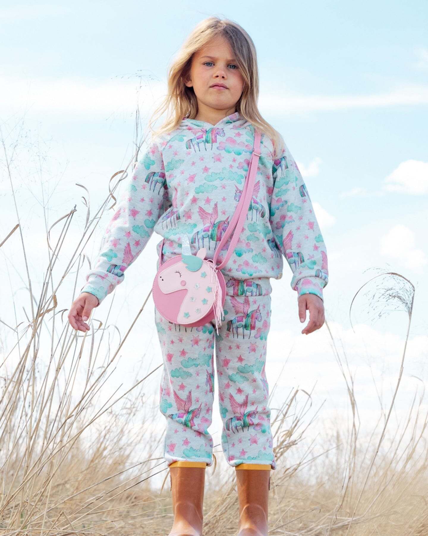 Girl wearing shiny French terry sweatpants and hoodie with unicorn print in outdoor setting