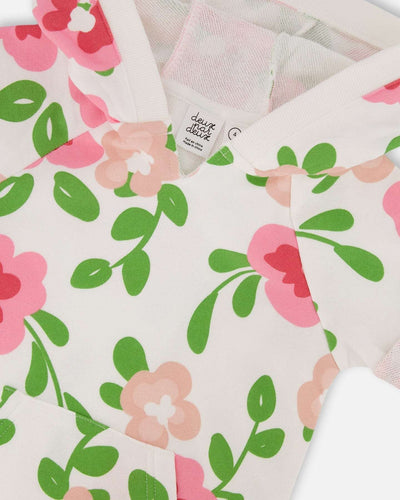 Close-up of printed French terry fabric with pink flowers and green leaves on white background from hooded dress