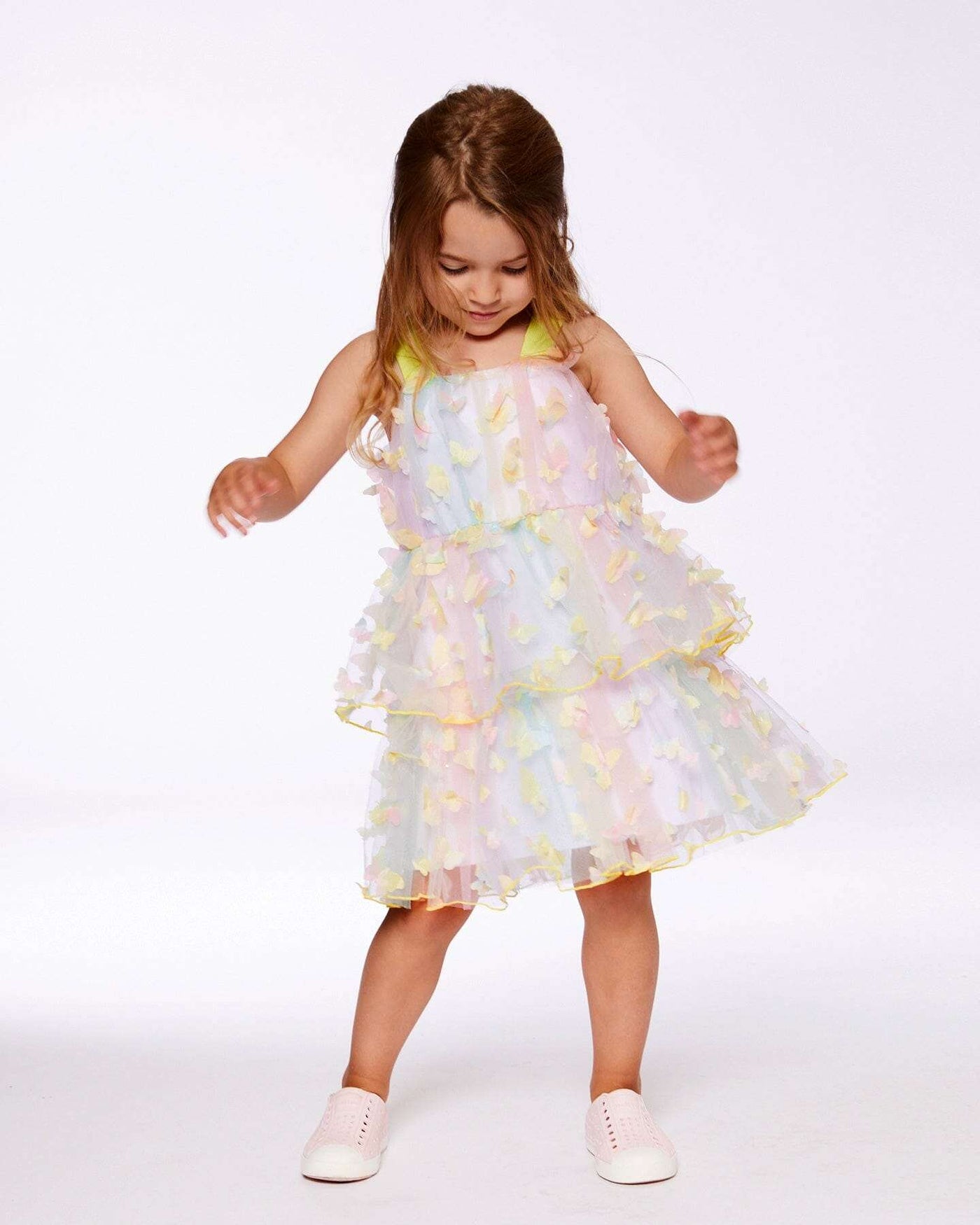 Little girl wearing a multicolored tiered printed mesh dress with butterfly appliques and wide straps