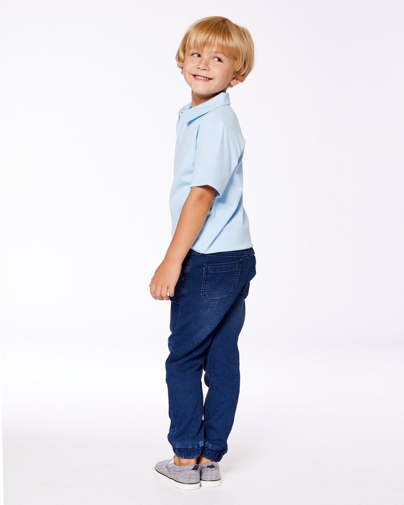 Boy wearing dark denim blue French Terry Denim Jogger pants with elastic ankles and a light blue polo shirt