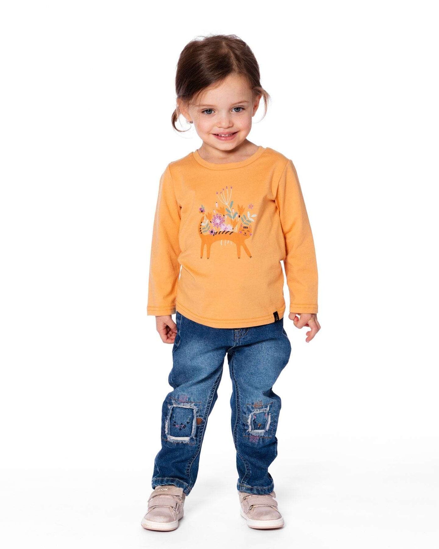 Toddler wearing blue denim jeans with embroidered patches and an orange long-sleeve shirt