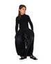 Girl wearing black wide leg pleated pants with elastic waistband and black long-sleeve top