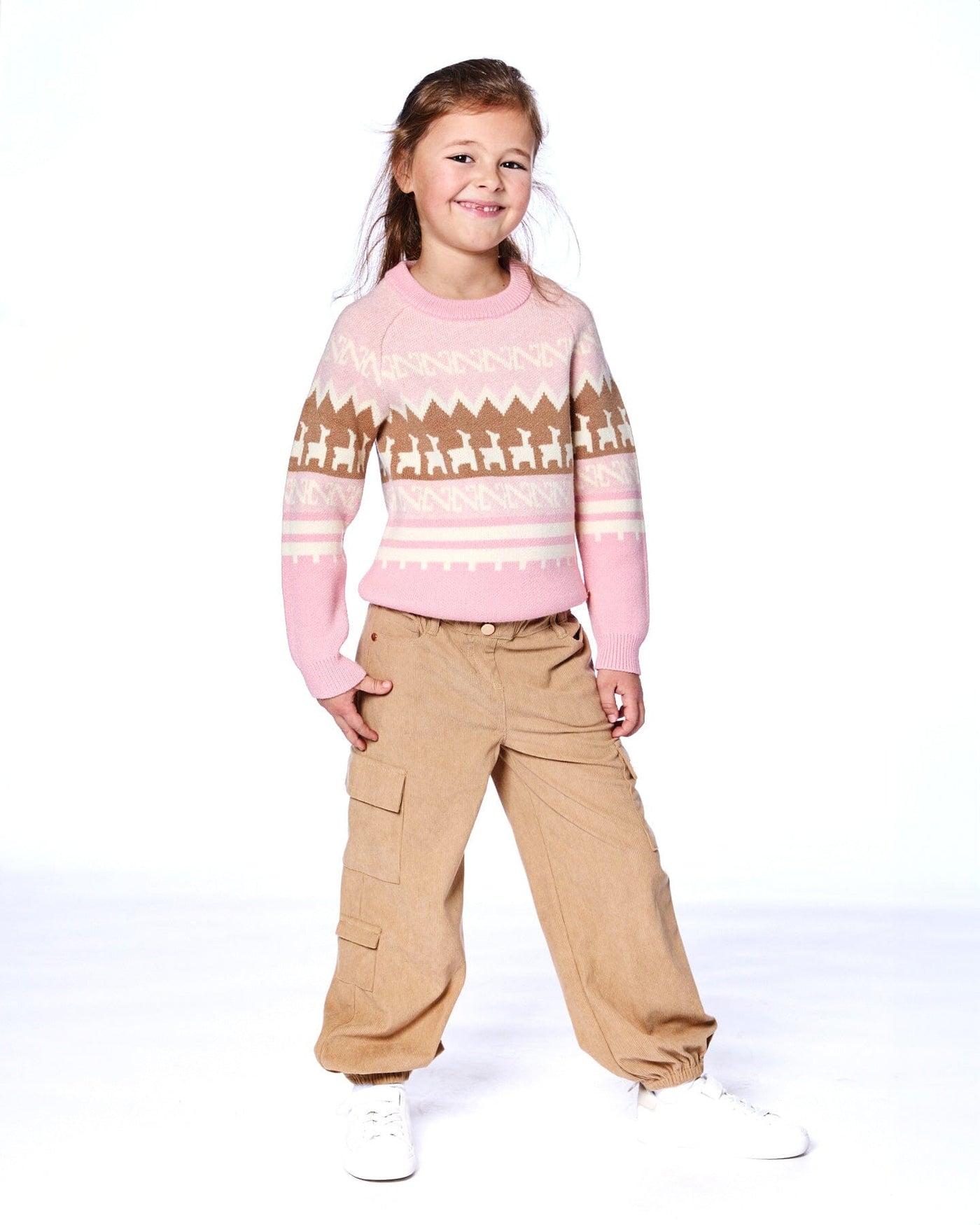Child wearing light pecan brown parachute corduroy pants with cargo pockets and elastic cuffs paired with a pink and brown patterned sweater