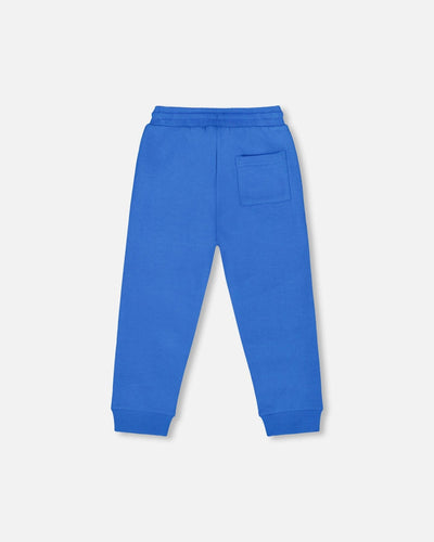 Blue fleece sweatpants with drawstring waistband, side pockets, seamed knees, and rib knit trim.