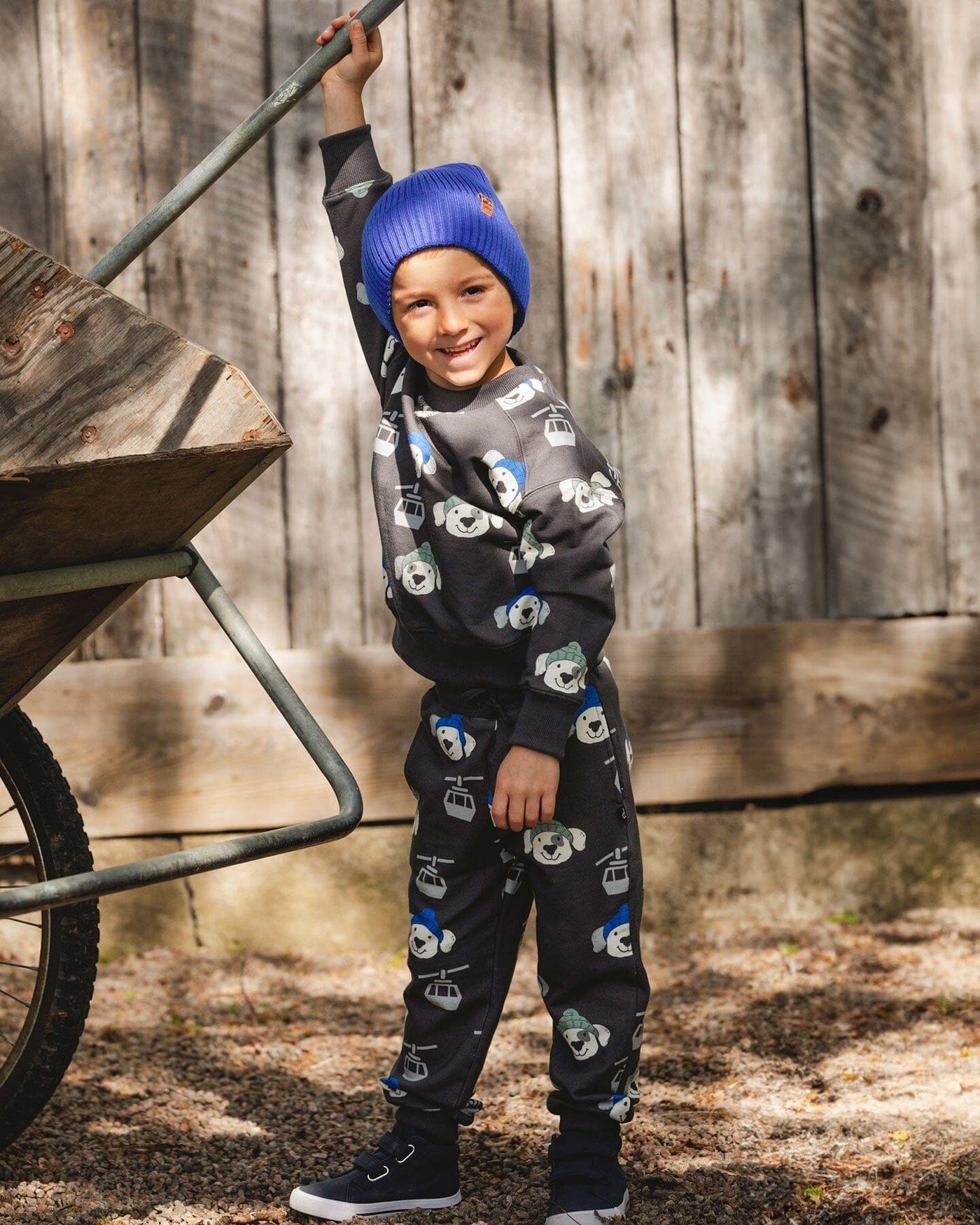 Child wearing gray fleece sweatpants with playful dog and ski gondola print outdoors