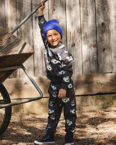 Child wearing gray fleece sweatpants with playful dog and ski gondola print outdoors