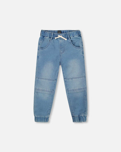 Light blue denim French Terry jogger pants with drawstring waistband, seamed knee panels, scoop front pockets, and elastic ankles for comfort.