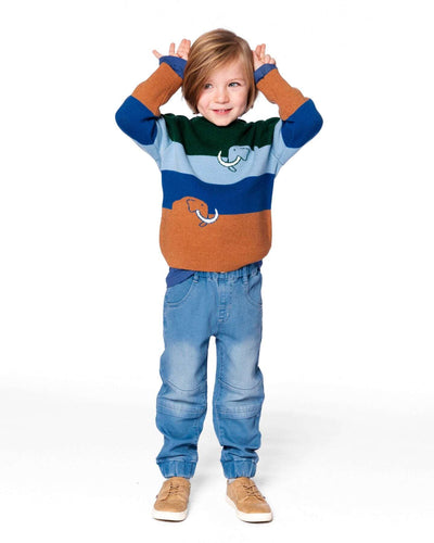 Child wearing light blue denim French terry jogger pants with elastic ankles and seamed knee panels, styled with a colorful sweater and tan shoes.