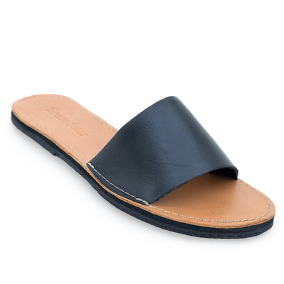 The Linda Leather Slide sandal with black leather upper, cushioned tan footbed, hand-cut sole from upcycled tires, and secure ankle strap for comfort