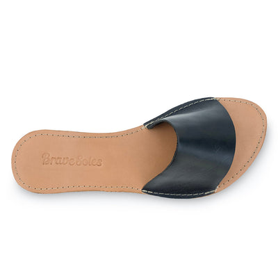 Top view of The Linda Leather Slide sandal with black leather strap and tan leather footbed embossed with Brave Soles logo