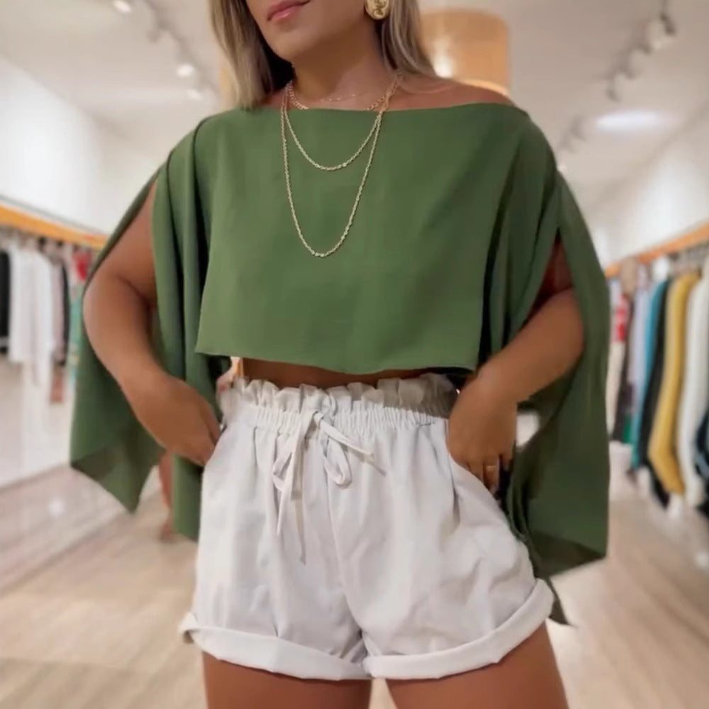 Woman wearing green off-shoulder top with bell split sleeves and white shorts in a boutique