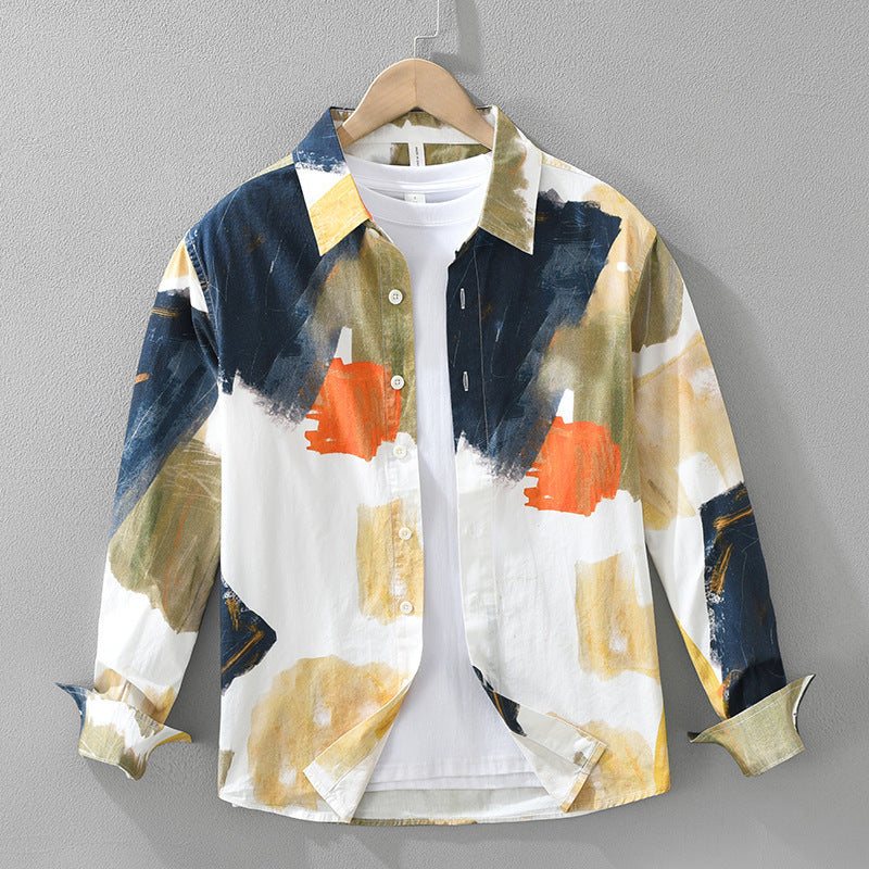 Loose fit long sleeve artistic casual cotton top with abstract paint print in blue, orange, and beige tones on hanger against gray wall