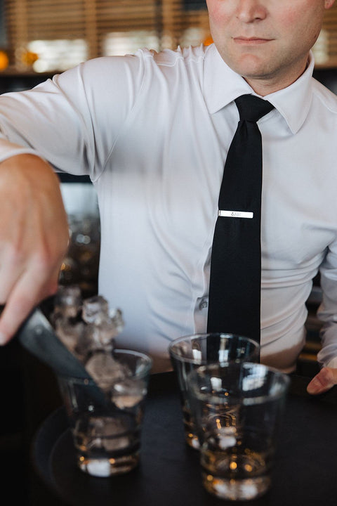 Man wearing a white Never-Iron Work Shirt with a black tie serving drinks at a bar